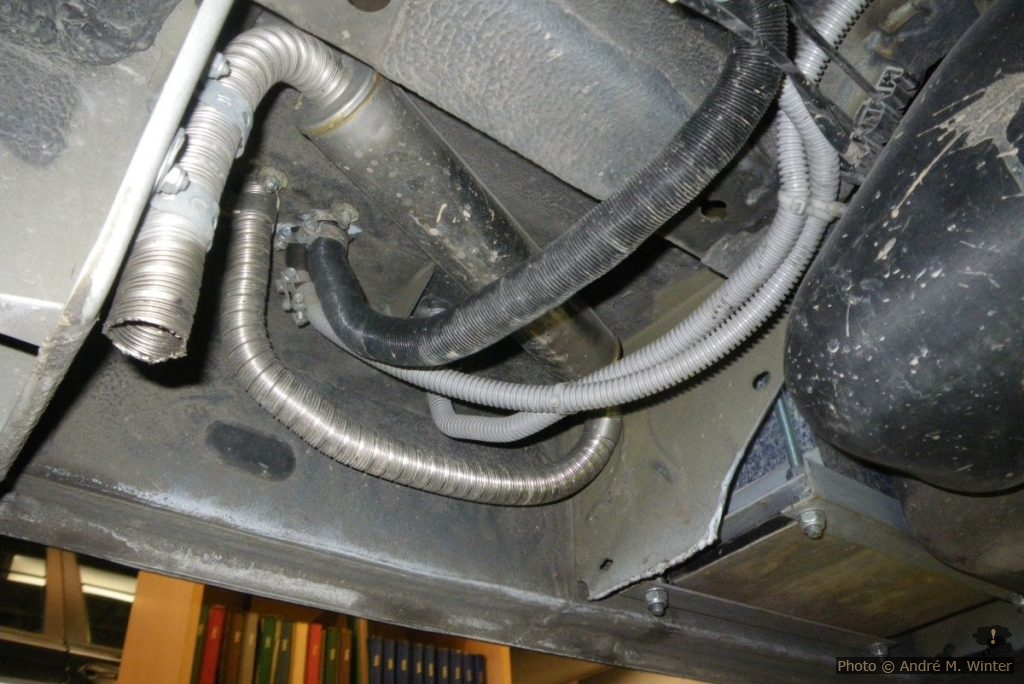 Der Auspuff macht hier eine vertikale Schlinge und es kann somit zu Kondenswasserstau kommen. Nach nun fünf Winterperioden, inklusive zwei Wochen Norwegen im März, konnten keine Probleme festgestellt werden. silber: Auspuff (Richtung egal). schwarz: Frischluftzufuhr für den Brenner. grauer Kabelschlauch dazwischen: die Dieselzufuhr. grauer Kabelschlauch rechts: Strom für die Dieselpumpe. Die Kabelschläuche laufen zusammen hinter den Tank, getrennt über den Tank (durch je zwei ausreichend grosse Löcher in den Querträgern, die Kabelstrang der Handbremse läuft durch die mittleren Löcher), anschliessend wieder zusammen vor dem Tank auf die rechte Seite am rechten Träger entlang bis zur Pumpe und zur Anschlussstelle.