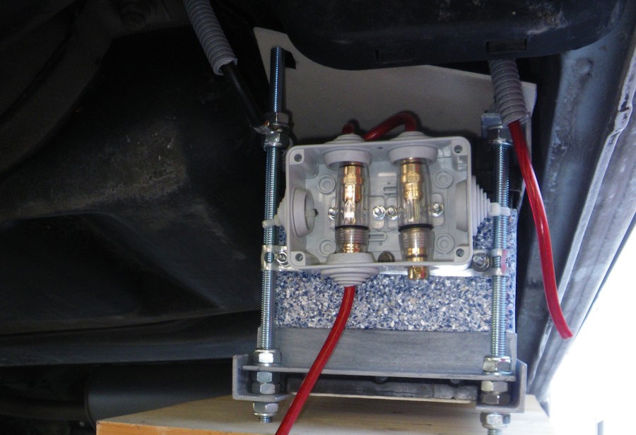 Eine Sicherung für die Strecke zur Startbatterie und die zweite für den Weg zum Schaltkasten im Inneren des Wagens. Die Kabelbox ist definitiv zu klein für die grossen Sicherungen, aber ich hatte keine andere. Auch sind die ausgehenden Pluskabel nicht ausreichend gegen Steinschlag geschützt (sie sollten alle oben rausgehen). Die Masse führt zurück zur Startbatterie.