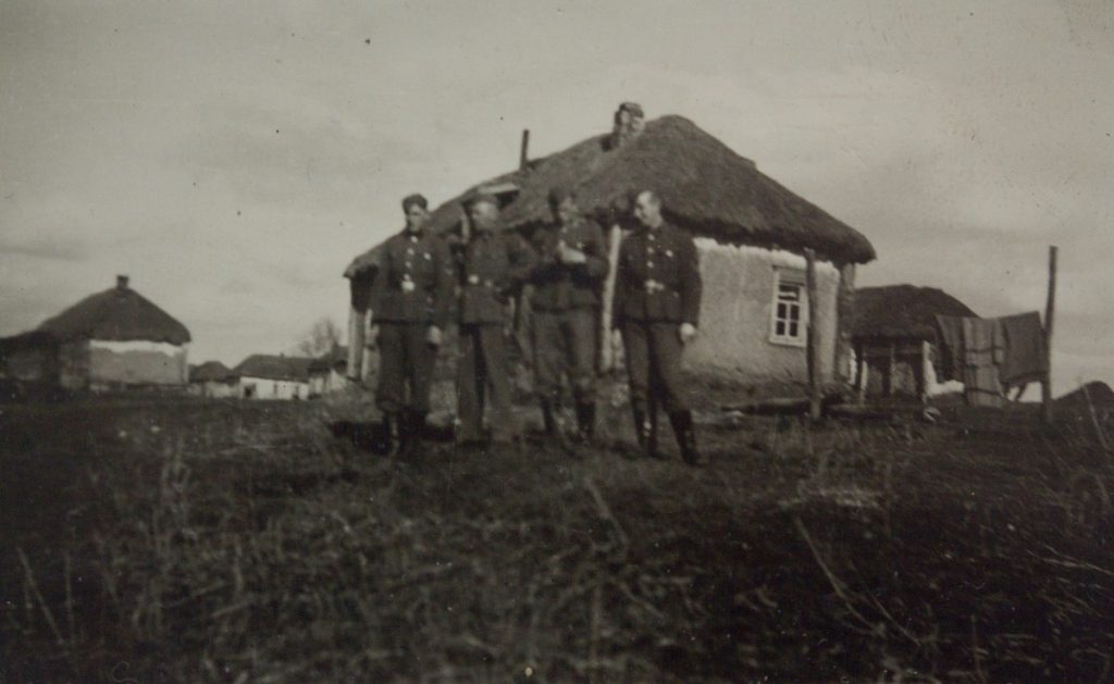 Bruno und drei andrer4 Waffen-SS-Soldaten bei Bauerhäuser aus Lehm mit Strohdach in Weissrussland